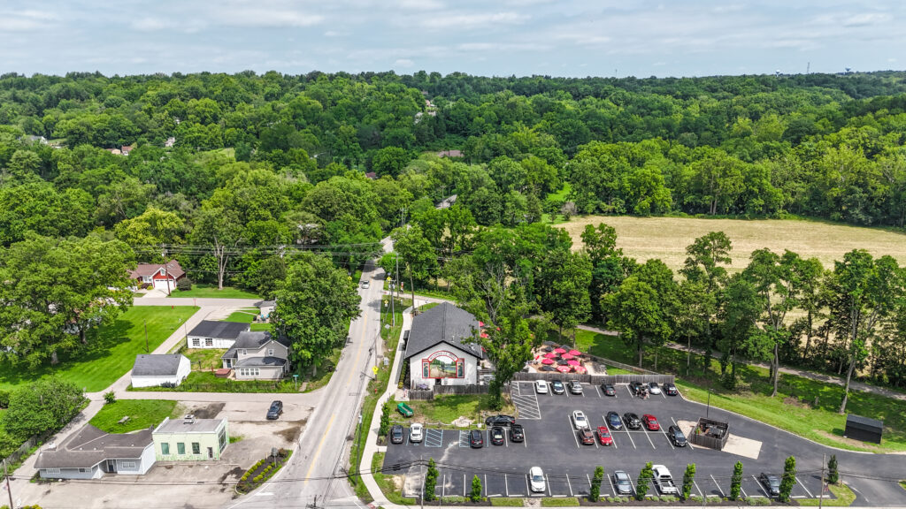 Aerial drone view of the area surrounding the future Trailside Estates development, showing nearby homes, local business, parking, and trail access.